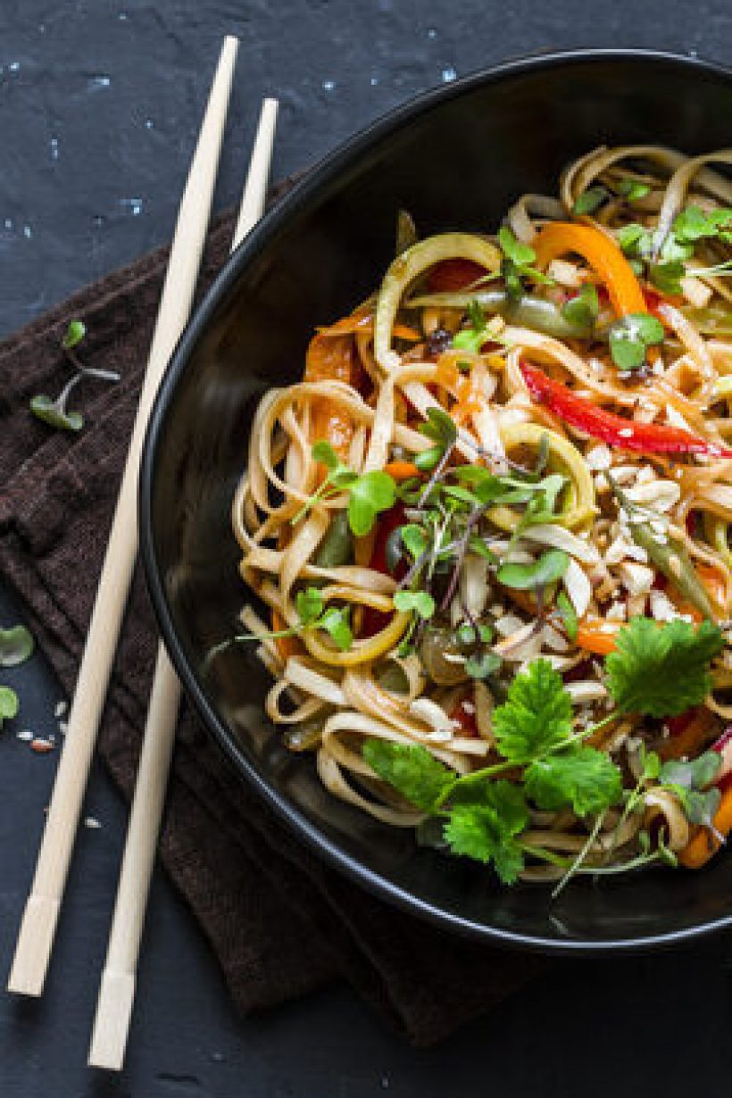 Pad Thai vegetarian vegetables udon noodles in a dark background, top view. Vegetarian food in asian style. Copy space